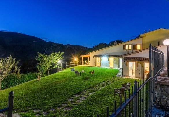 Evening view of the villa with illuminated garden and hillside backdrop - Acquanera