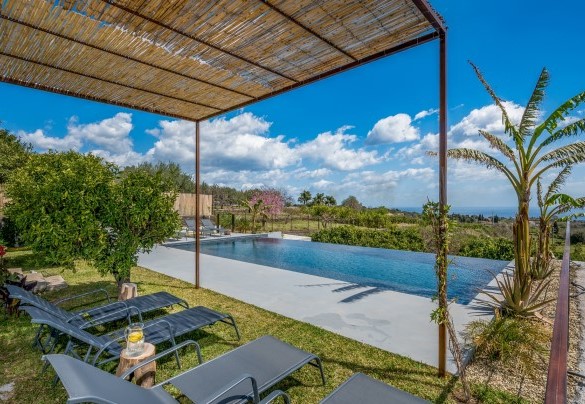 Dei lettini sono disposti sulla zona col prato ombreggiato sotto un pergolato - Agrumé Country House
