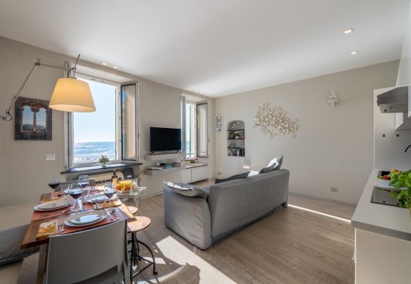 Open-plan area including the living room with a double sofa bed, the kitchen, and the dining table – Aurora