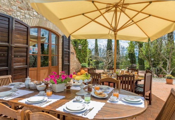 La zona pranzo esterna, allestita con tavolo, sedie e ombrellone - Borgo dei Cipressi