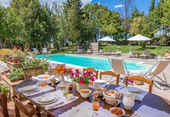 La zona pranzo esterna, allestita con tavolo, sedie, ombrellone e lavello in pietra antica - Borgo dei Cipressi