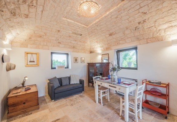Il living space del “trullo Saraceno” completo di tavolo con sedie e poltrona - Borgo dell’Agrumeto