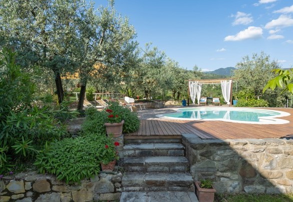 Nell’area prendisole, in legno e pietra lungo il perimetro e poi a prato punteggiato da ulivi nell’area circostante, sono disposti lettini, ombrelloni e un gazebo in legno arredato con poltroncine – Buca delle fate