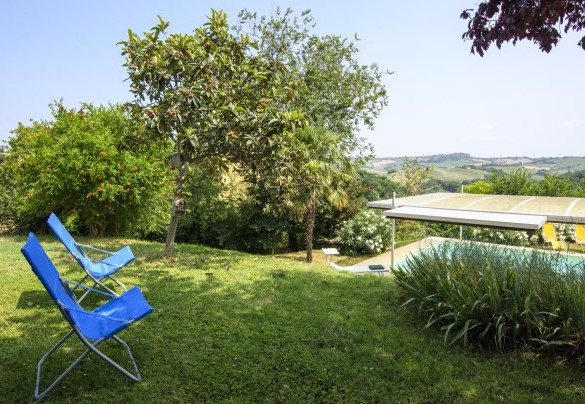 Giardino con sedie e vista sulla piscina – Ca Lucciola