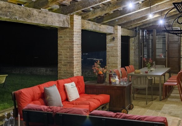 Porch with sofas and dining table lit for the evening - Ca Seppe