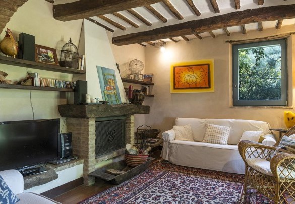 Il salotto al piano terra con tv e caminetto, comunicante con la cucina   –  Campodalto 