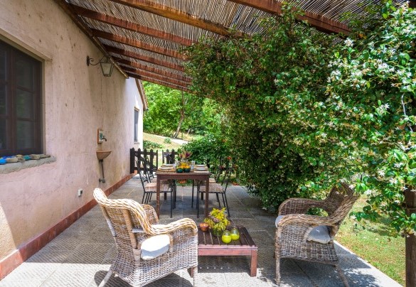 All’esterno della cucina una pergola, avvolta da profumate piante di gelsomino rampicanti, è attrezzata con tavolo e sedie per mangiare all’aperto, immersi in un’atmosfera che ispira pace e tranquillità - Casa al fiume