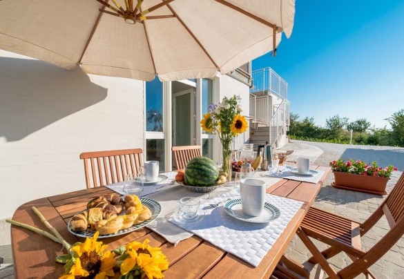 Outdoor dining area equipped with table and chairs under an umbrella - Casa di Eolo 8+2