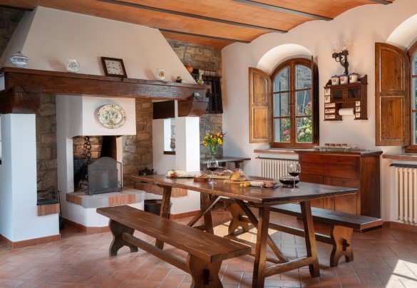 L’ambiente open space in cui si trova un salone con tavolo e con camino e la cucina in muratura al piano terra – Casa Paggetti