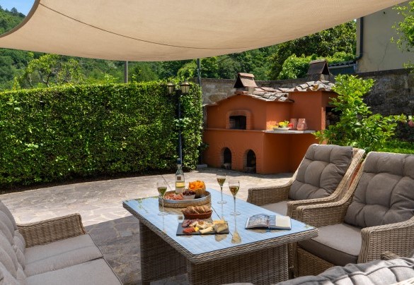 Il salotto all’aperto con vela, ideale per rilassarsi e godersi la tranquillità. Adiacente al salotto si trova il barbecue in muratura e il forno a legna – Casa Paggetti