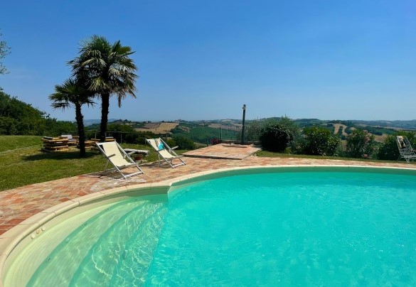 Poolside area with loungers and palm trees, overlooking the hilly landscape - Casa Zefiro