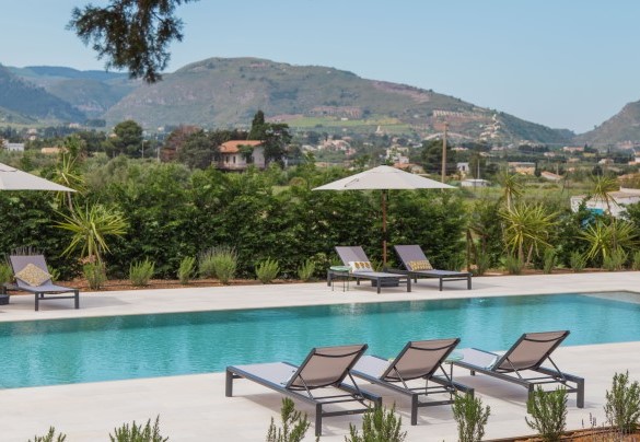 Intorno alla piscina sul vasto solarium lastricato in pietra naturale sono posizionati lettini ed ombrelloni – Casale Buccellato