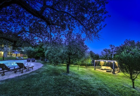 Gazebo illuminated with soft decorative lights, featuring an outdoor lounge - Casale degli Ulivi