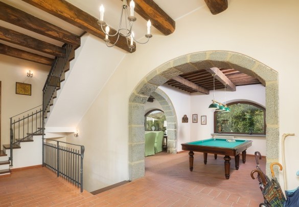 La scala per il primo piano e per il piano seminterrato, la porta del bagno di servizio, il living con tavolo da biliardo e salotto – Casale del Castagneto