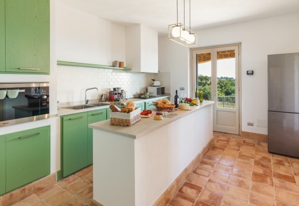 La cucina completamente accessoriata e con isola ha la french door con uscita su un secondo portico accanto alla scala esterna (17 gradini) per il primo piano - Casale Grottini