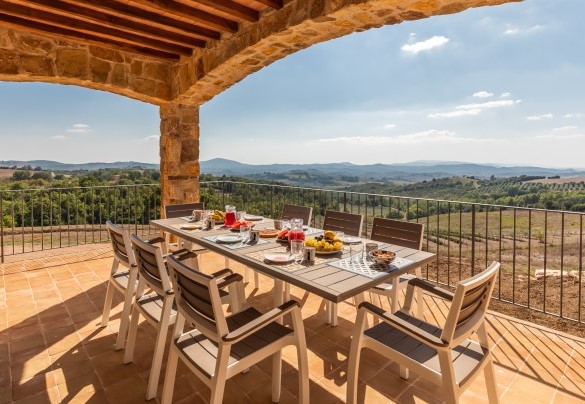 All'uscita delle french doors dell’open space al piano terra si trova il porticato arredato con tavoli e sedie per mangiare all’aperto - Casale Grottini