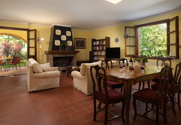 Il salotto al primo piano con divano, poltrona, camino, tavolo e sedie - Casale Il Torchio