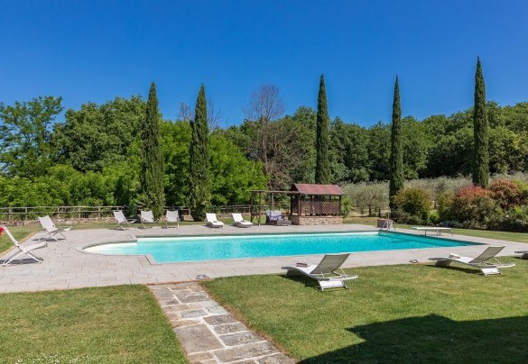 Il bordo piscina lastricato in pietra e circondato da superfici a prato - Casale La Splendida