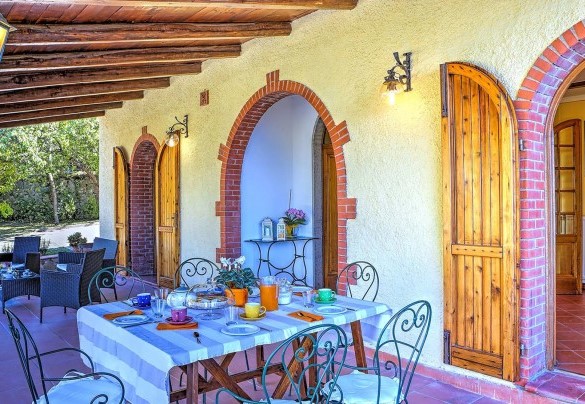 The porch shades the table prepared for outdoor breakfast – Casale Le Conce 