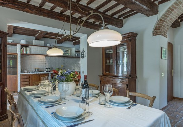 La cucina con tavolo da pranzo, la porta del bagno di servizio e l’ingresso secondario - Casale Le Querce di Cetona