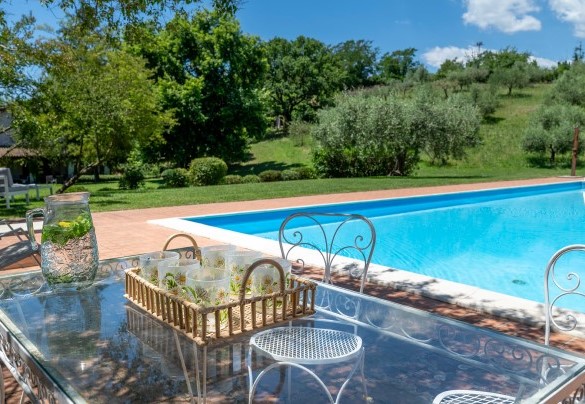 Arredi a bordo piscina ombreggiati dal verde naturale – Casale Le Querce