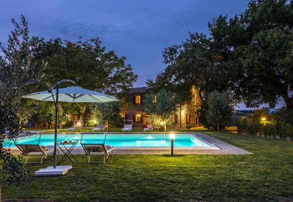 The pool and the farmhouse in the background lit up at sunset - Casale Le Tre Querce