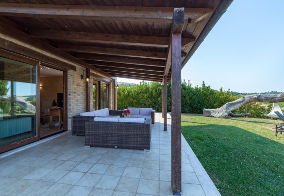 Elegant panoramic lounge equipped with a table and sofas under a wooden pergola - Casale Rosy 6+2