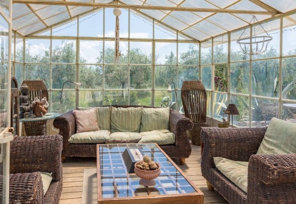 The welcoming glass greenhouse, now used as a sitting room, finely furnished and with ceiling fan - Casale Santa Lucia
