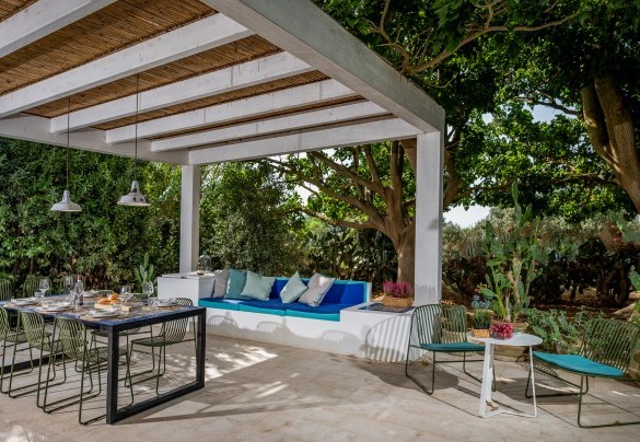 Zona pranzo esterna sotto la pergola circondata dagli alberi - Casavento Puzzitteddu