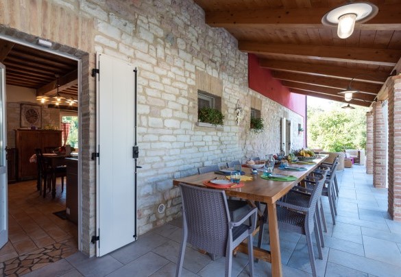 Ampio porticato arredato con tavolo e poltroncine per mangiare all’aperto – Cascina Marianna