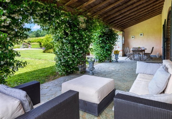 The cozy furnished porch overlooking the large flat lawn at the bottom of which emerges the pool from the original shape of small pond - Cascina Moglia