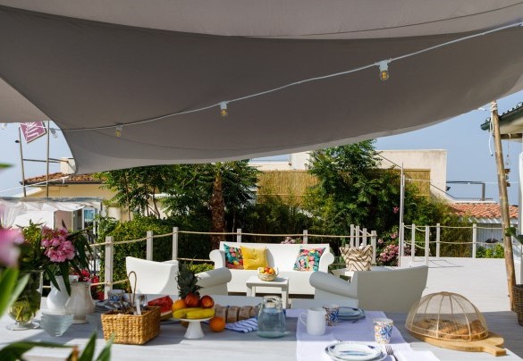 La casa è abbracciata da una banchina rialzata in legno naturale dove si trova la zona solarium e relax con lettini, una grande tavola da pranzo, divano, poltrone – Casetta del Pescatore