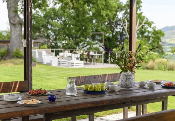 Outdoor dining area under wooden pergola with wood table and garden view - Checello
