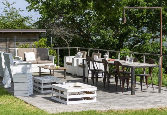 Lounge area with wooden tables, chairs and sofas on an outdoor deck - Checello