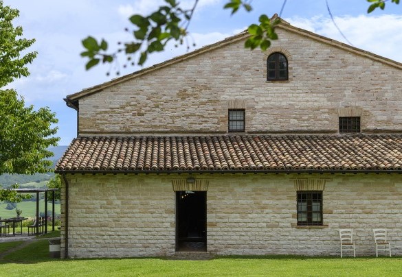 Stone side facade of the villa with door and windows overlooking the lawn - Checello