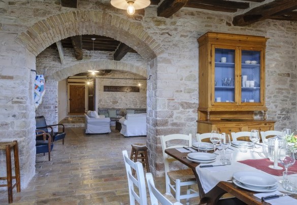 Overall view between dining room and living area, connected by arches and exposed brick - Checello