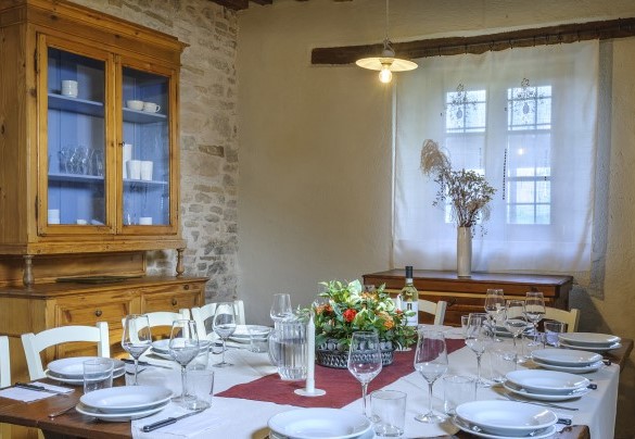 Dining room with long table, wooden chairs, and antique cupboard - Checello