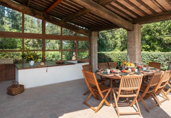 On the covered, tiled patio is the outdoor dining area, connected to the dining room inside the villa - Cosciano