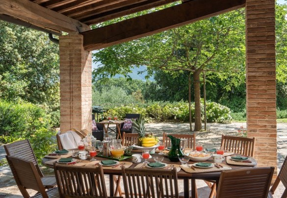 On the covered, tiled patio is the outdoor dining area, connected to the dining room inside the villa - Cosciano