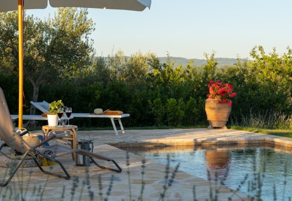 La piscina è rivestita in travertino color noce, dispone di gradoni di accesso su un lato corto e di un faro interno – Country House Lo Spigo