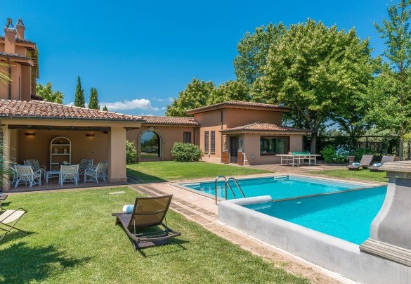 The pool immersed in the green lawn and the house in the back ground – Montepietraia– Country House Montepietraia e San Martino 