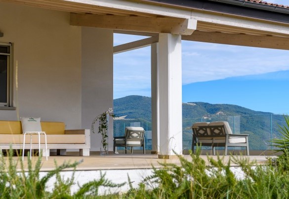 Back porch with wooden ceiling and contemporary style seating, overlooking the green hills and entrance to the first floor rooms - Dimora Montefalcone