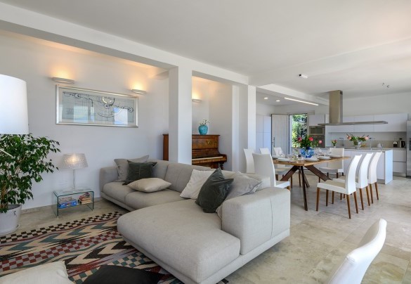Spacious living room with a sofa, large glass windows brightening the space, and a view of the pool - Dimora Montefalcone