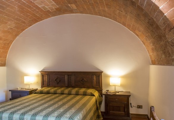 Il letto matrimoniale avvolto dall'arco in muratura - Fattoria L'Olmo Rosso