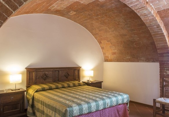 Il letto matrimoniale avvolto dall'arco in muratura - Fattoria L'Olmo Rosso