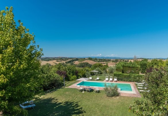 La piscina, in bella posizione panoramica al centro del giardino, si raggiunge dagli ingressi del casale percorrendo pochi passi attraverso il prato - Finestra su Siena