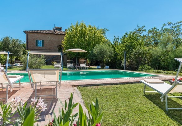 La piscina è bordata dalla  zona prendisole con lettini e ombrelloni - Finestra su Siena