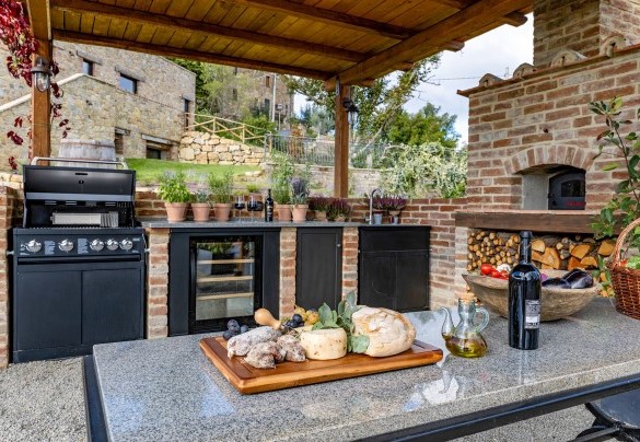 Under a pergola is the outdoor kitchen with pizza oven, gas barbecue and dining area - I Tramonti