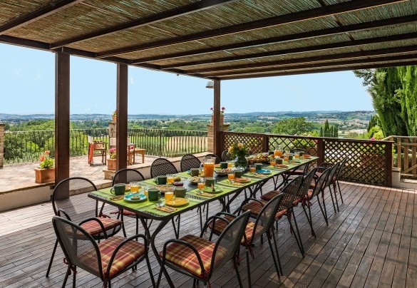 La zona pranzo esterna sotto la pergola, allestita con tavolo, sedie e cucina - Il Borgo  