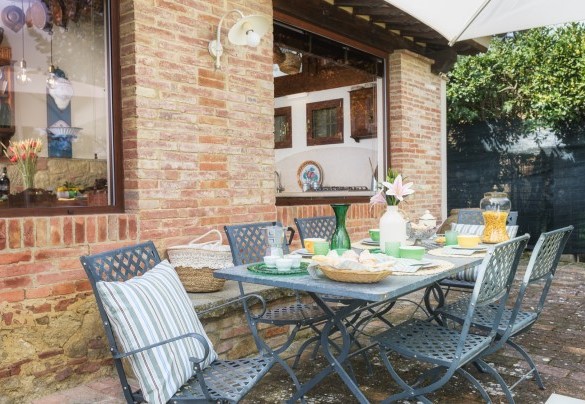 La zona pranzo esterna, allestita con tavolo, sedie e ombrellone - Il Fienile